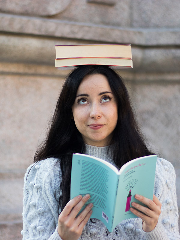 Chiara Giglio con un libro in mano e una pila di libri in testa